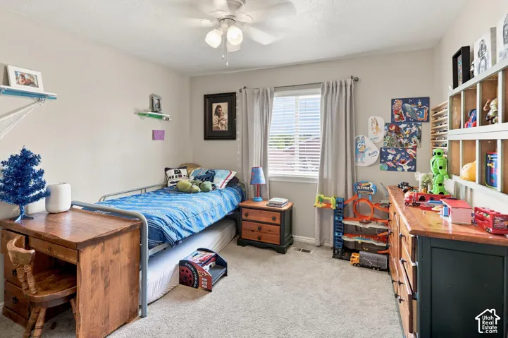 Light-colored walls, carpeted flooring, and a ceiling fan with integrated lighting