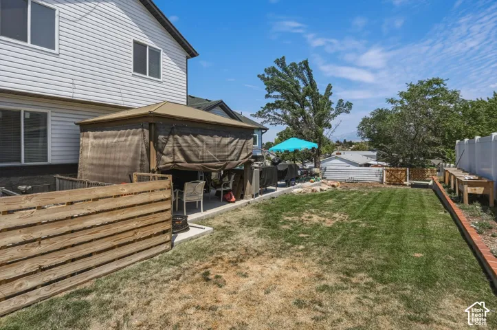 Spacious backyard featuring a rectangular lawn, concrete patio, and a covered gazebo