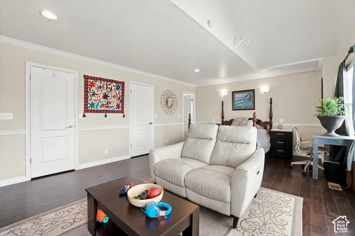 Dark wood-finish flooring with crown molding and recessed lighting