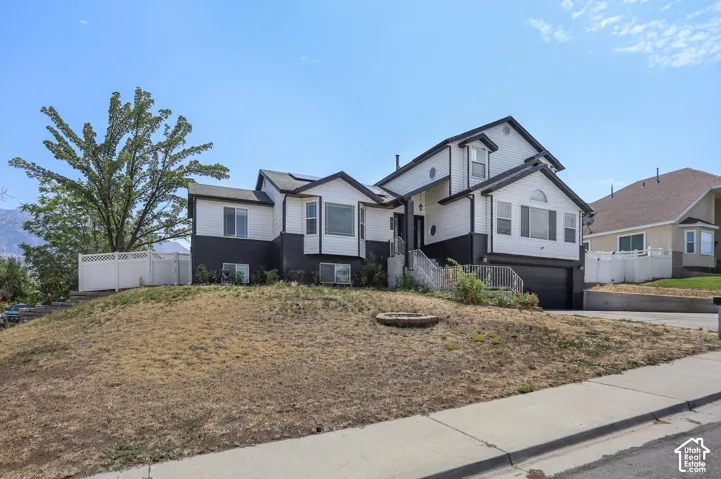 Two-story residence with a two-tone exterior, attached garage, and a white picket fence