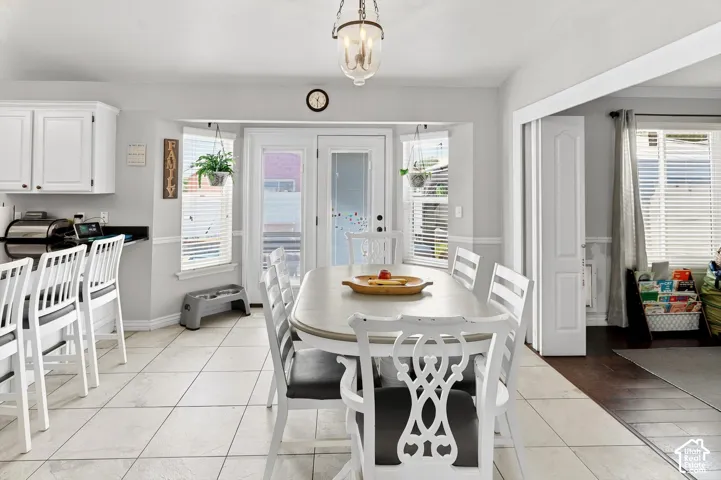 Tiled flooring extends through the dining area with a bay window and a pendant light fixture