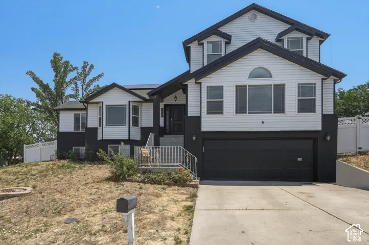 Two-story residence featuring white siding and black trim, an attached two-car garage, multiple bay windows, and a front entry with steps and railings