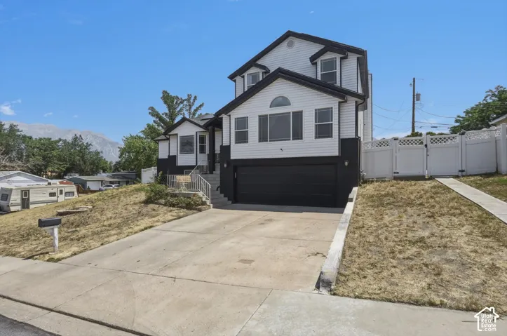 Two-story residence featuring white siding and black accents, a prominent two-car garage, and a concrete driveway