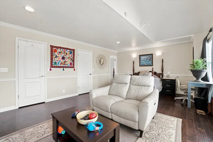 Dark wood-finish flooring with crown molding and recessed lighting
