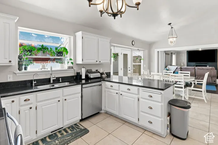 White cabinetry with dark countertops, stainless steel dishwasher, central island, and tiled flooring