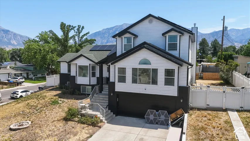 Modern two-story residence featuring a clean white exterior with black accents, peaked roofline with dual gables, and multiple large windows providing natural light