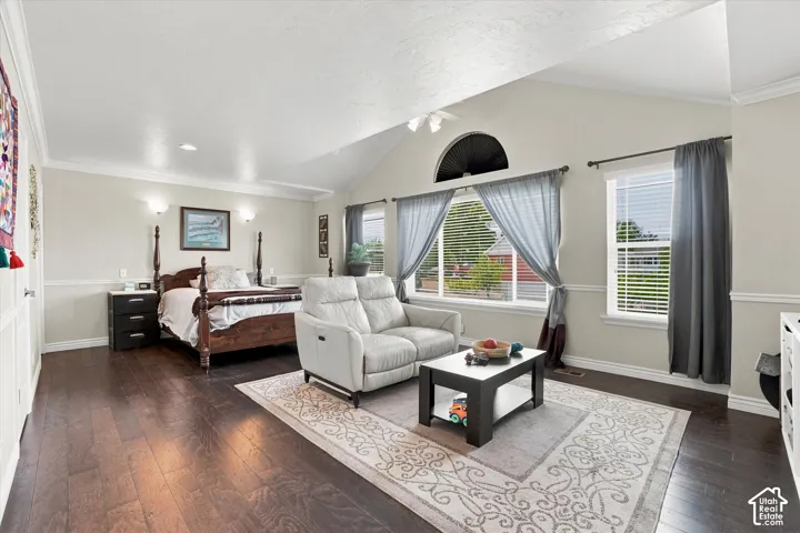 Vaulted ceiling, dark wood-finish flooring, half-round architectural window, recessed lighting, and crown molding