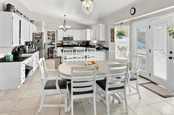 Vaulted ceiling, recessed lighting, tile flooring, white cabinetry, and French doors
