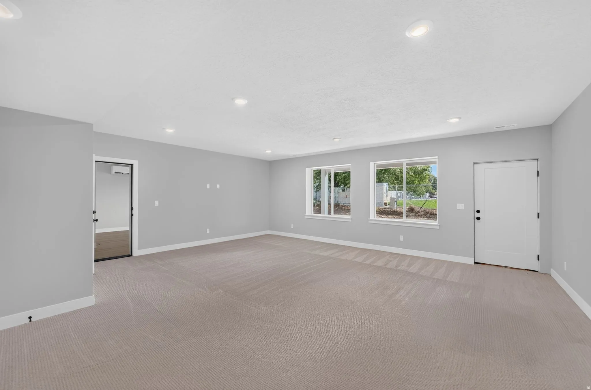 Recessed lighting, light gray wall finishes, light carpeting, white trim, and two windows