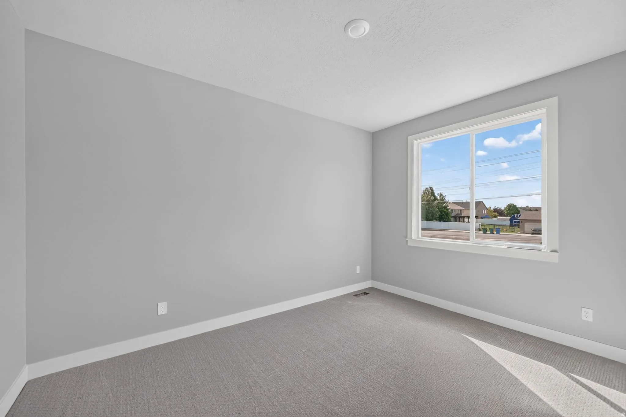 Neutral gray wall paint, white trim, gray carpeting, and a large window with white framing