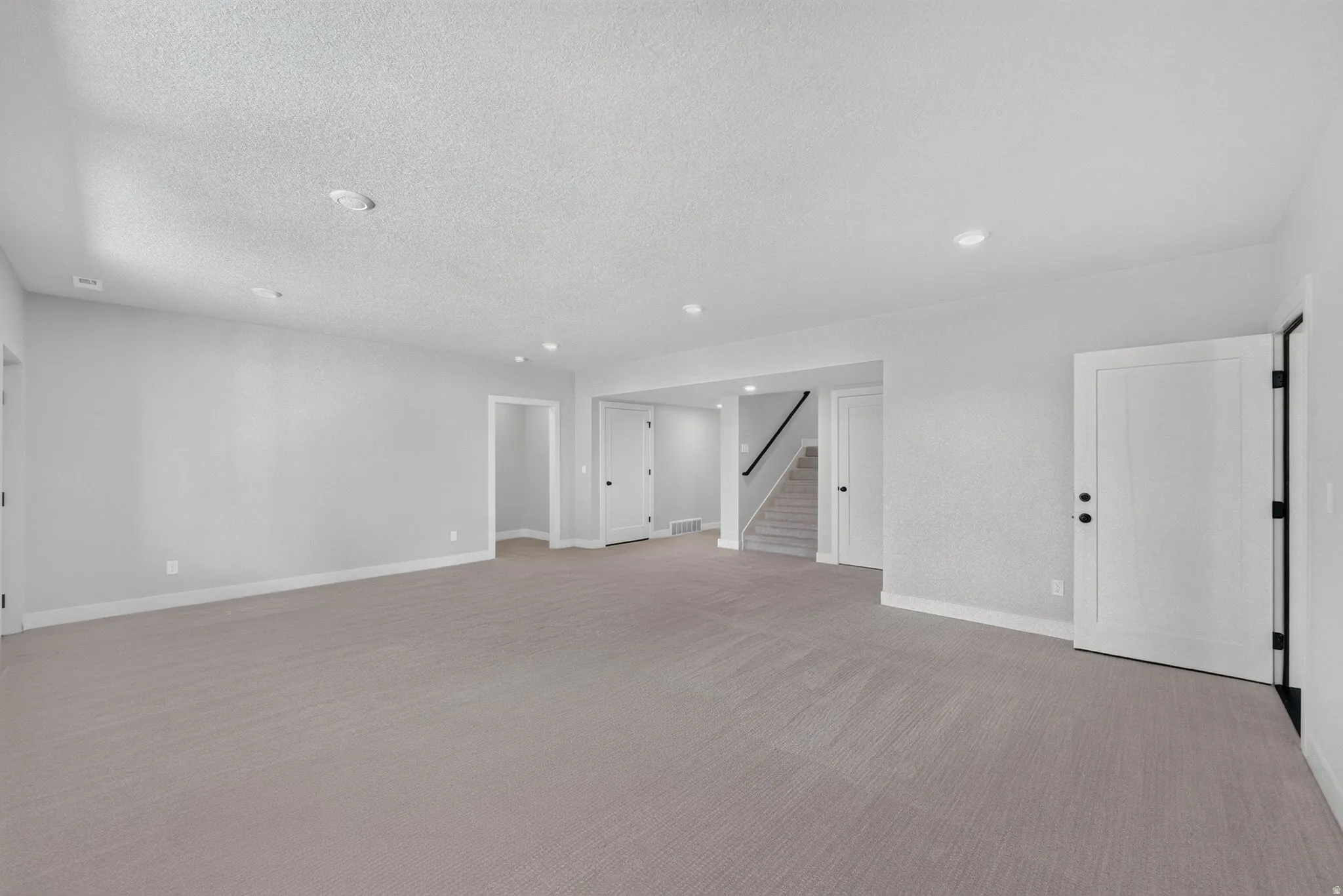 Spacious room with grey carpeting, white trim, and white paneled doors