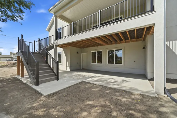 Lower-level patio with concrete surfacing, dual exterior lighting fixtures, and direct access to upper-level decking via stairs with metal railings
