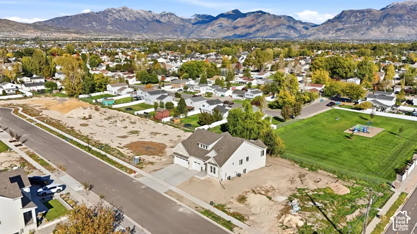 Aerial perspective featuring a multi-gabled residence with a shingled roof, attached garage, and prominent mountain backdrop