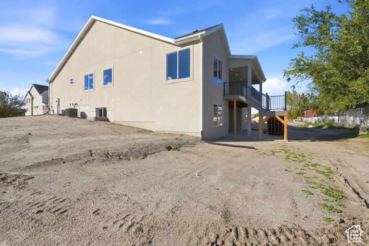 Two-story exterior with a neutral stucco finish, elevated back deck with metal railing, and staircase