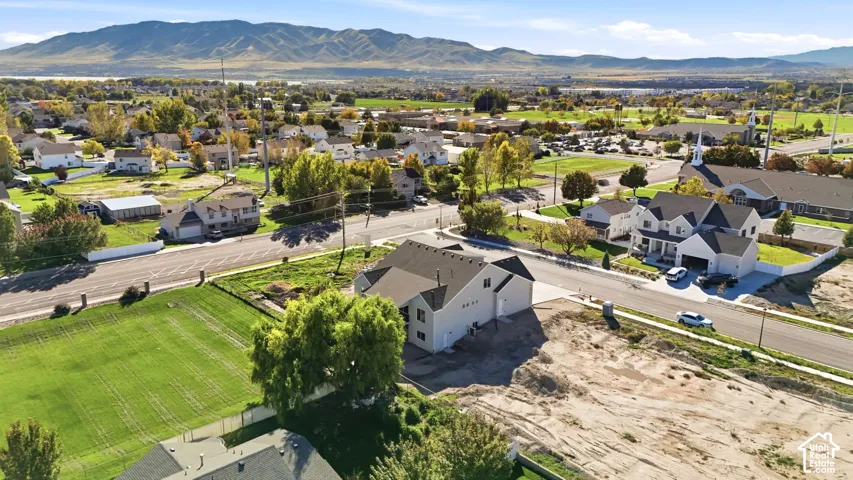 Aerial perspective showcasing a residential lot with mountain backdrops, paved street access, and established landscaping