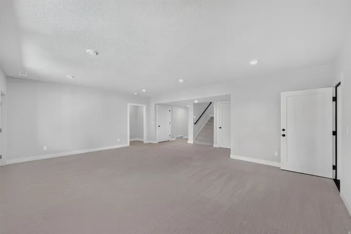 Spacious room with grey carpeting, white trim, and white paneled doors