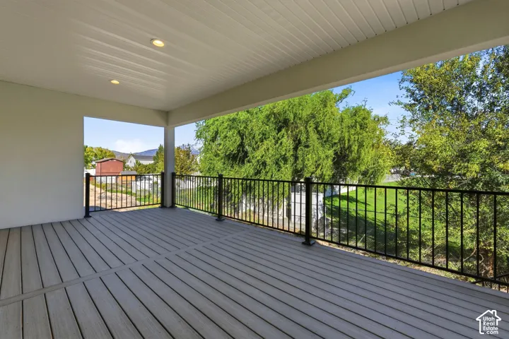 Covered deck featuring composite decking, black metal railing, recessed lighting, and a beadboard ceiling