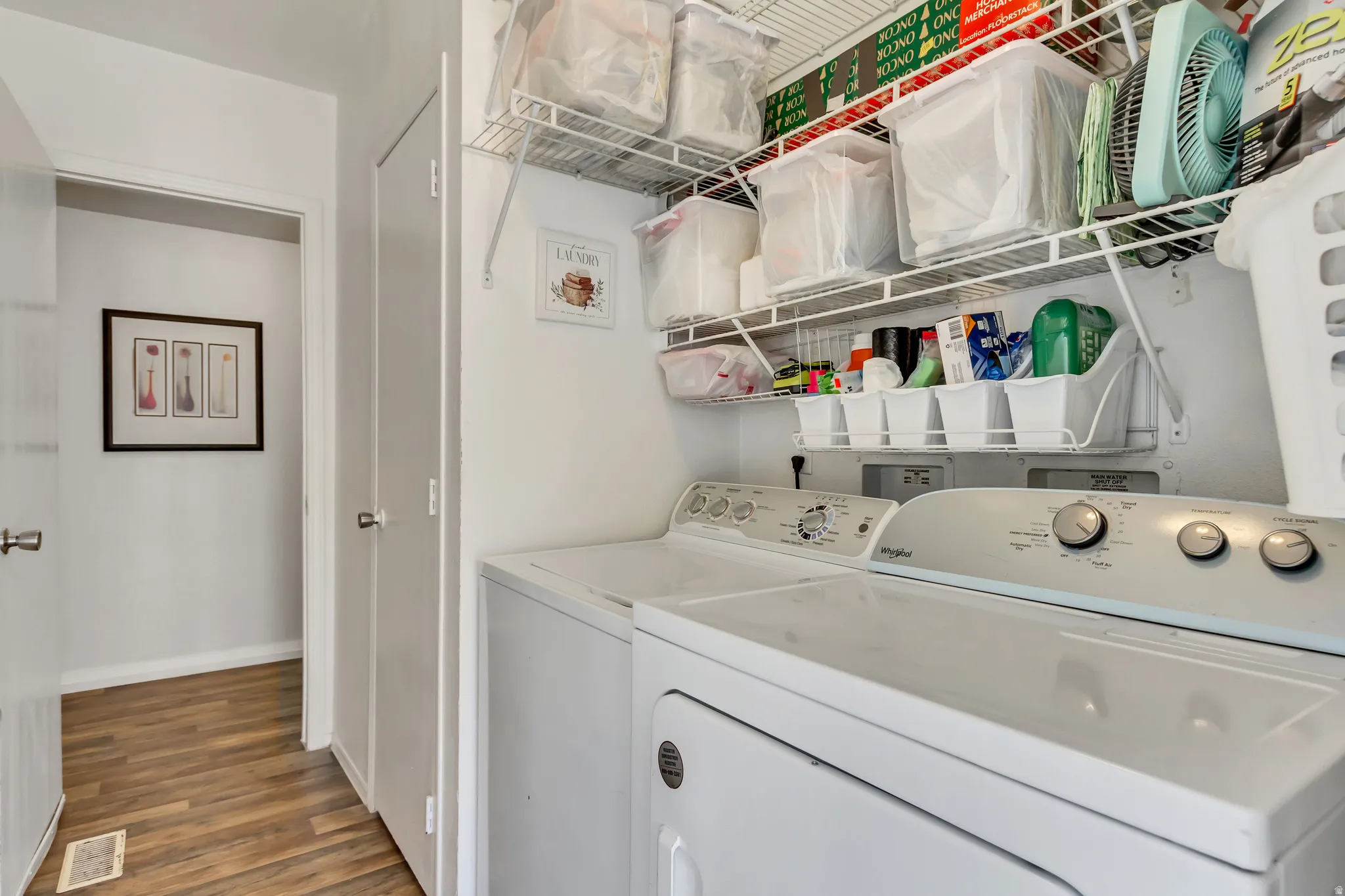 Laundry area with a full-size washer and dryer, wire shelving, and wood-finish flooring