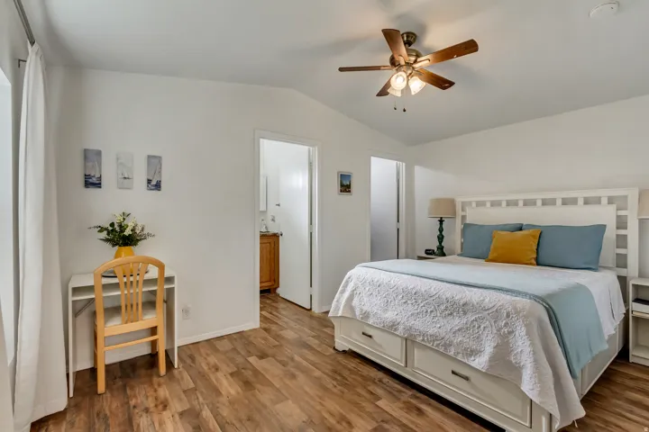 Wood-finish flooring, white walls, and a ceiling fan with integrated lighting