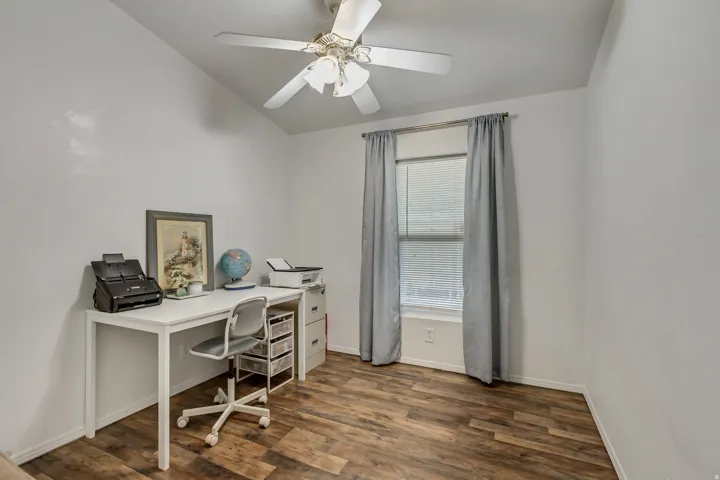 Vaulted ceiling, wood-finish flooring, ceiling fan, and window with blinds
