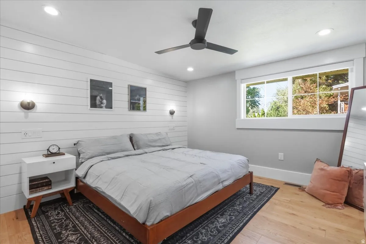 Shiplap accent wall with built-in sconces, wood-finish flooring, recessed lighting, and a ceiling fan