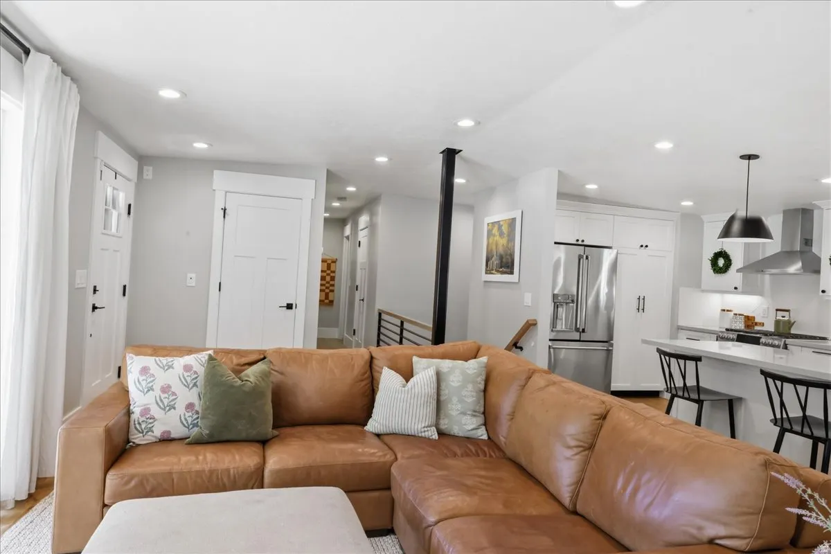 Recessed lighting, stainless steel appliances, white cabinetry, a kitchen island, and a range hood
