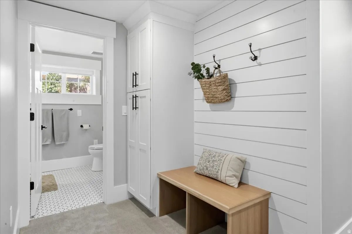 White shiplap accent wall, built-in storage bench, and tall built-in cabinetry with black hardware