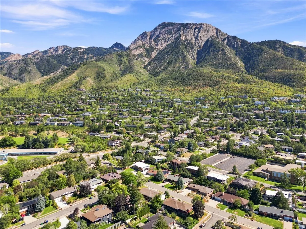 Mountain backdrop, residential area, mature trees, paved roads, clear skies
