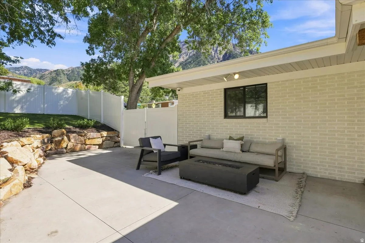 Concrete patio with an overhead soffit, light-colored brick exterior, and a rock retaining wall