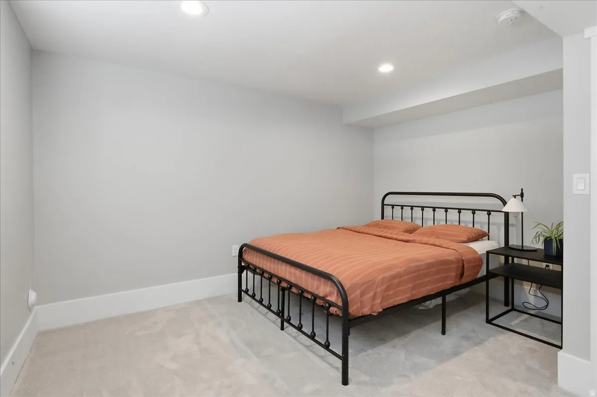 Recessed ceiling lighting illuminates a room with light gray walls and light-colored carpeting