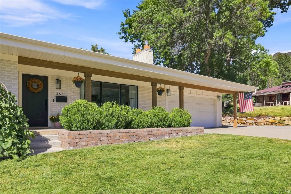 White brick exterior featuring a covered entry, dark wood-finish columns, a dark entry door, and an attached garage