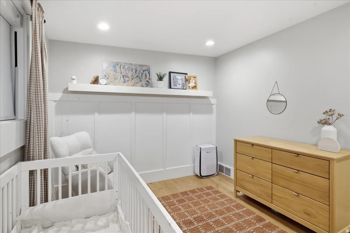 Recessed lighting, wood-finish flooring, white board and batten wall treatment, white wall shelving, and light gray wall paint