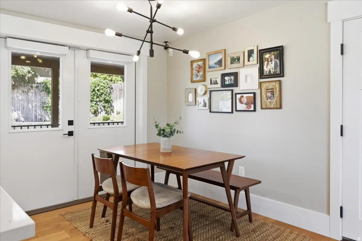 Bright dining area with wood-finish flooring, large dual French doors with transoms opening to exterior space, and a modern sputnik-style ceiling fixture