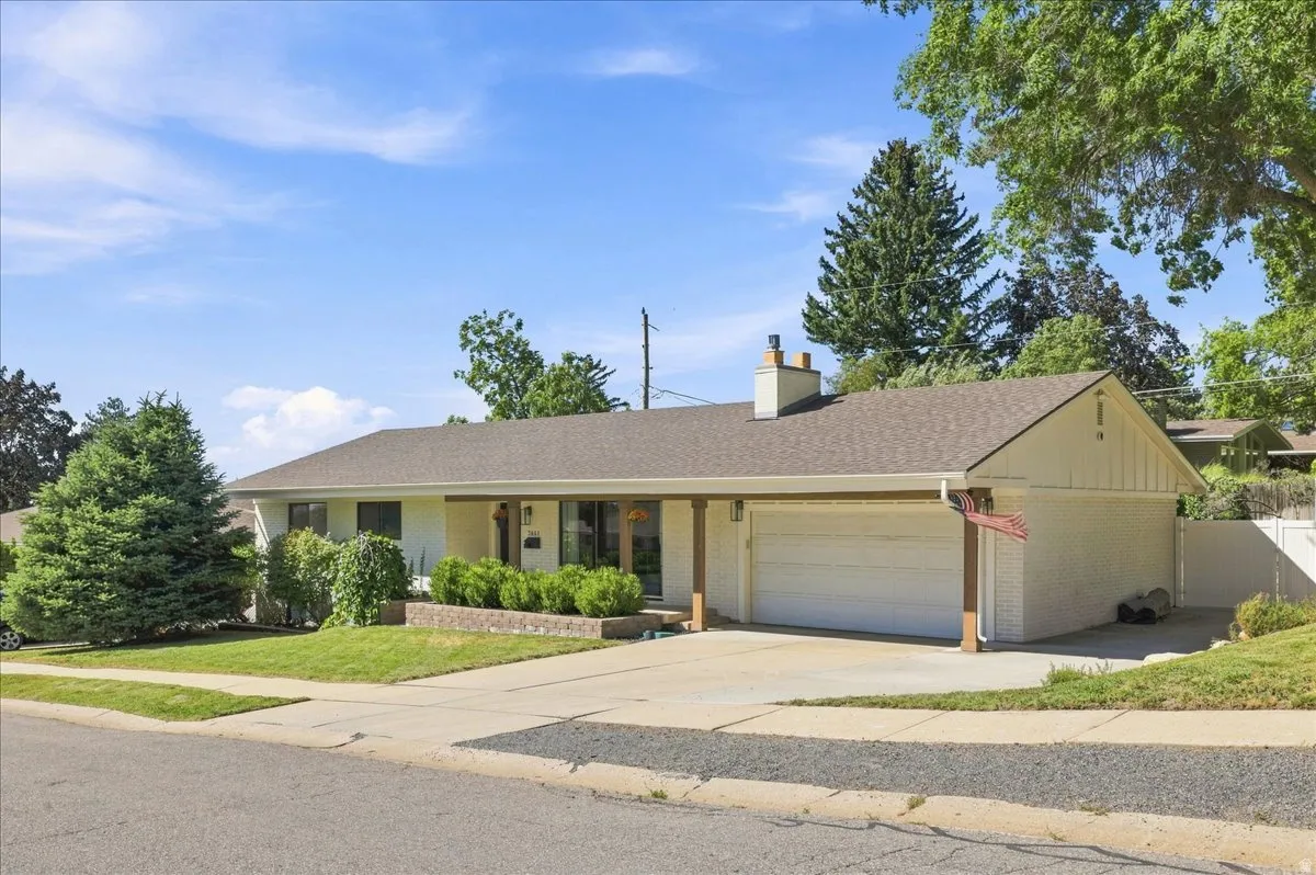 Single-story residence featuring a two-car garage, pitched shingle roof, and a brick chimney