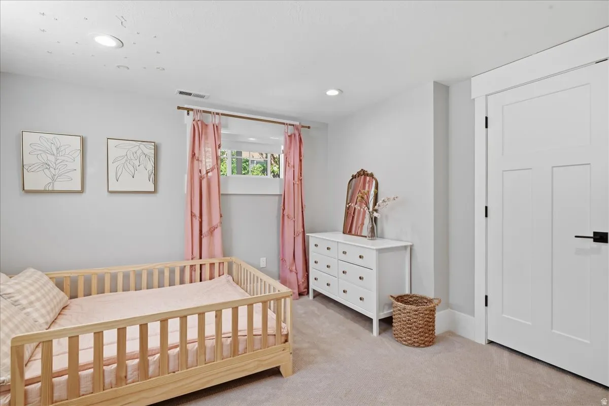 Recessed ceiling lighting, white painted walls, window with trim, and a white interior door with black hardware
