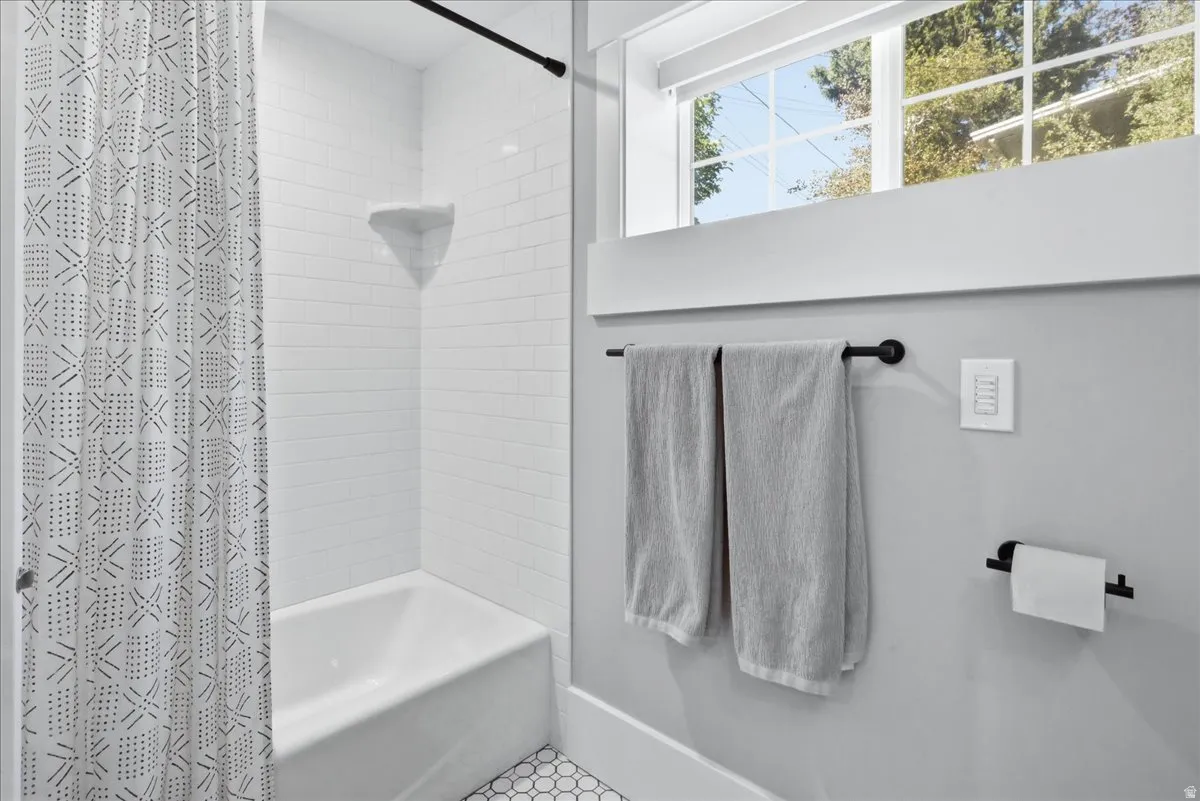 Bathtub with white subway tile surround, integrated corner shelf, and hexagon tile flooring