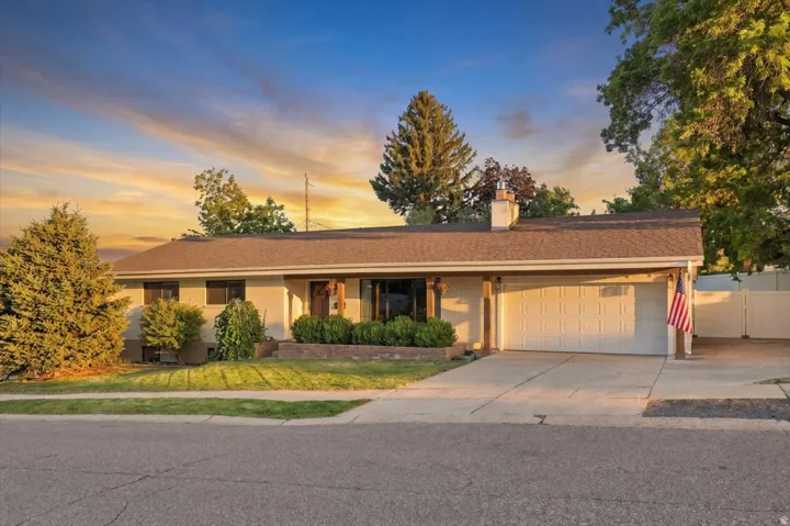 Single-story residence featuring a two-car garage, mature landscaping, and a fenced side yard