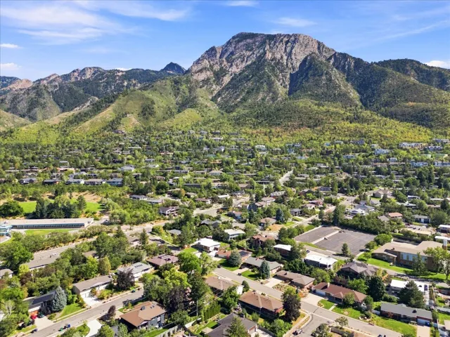 Mountain backdrop, residential area, mature trees, paved roads, clear skies