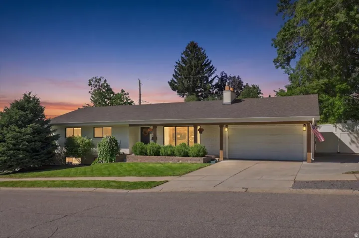 Single-story residence featuring a covered entry, attached garage, concrete driveway, and mature landscaping