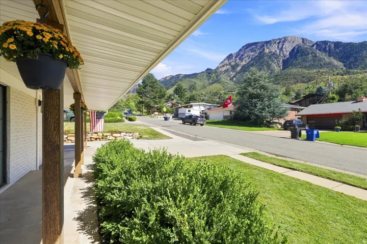 Covered front porch with wood-finish support columns, a concrete walkway, and manicured landscaping
