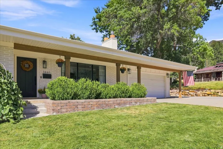 White brick exterior featuring a covered entry, dark wood-finish columns, a dark entry door, and an attached garage
