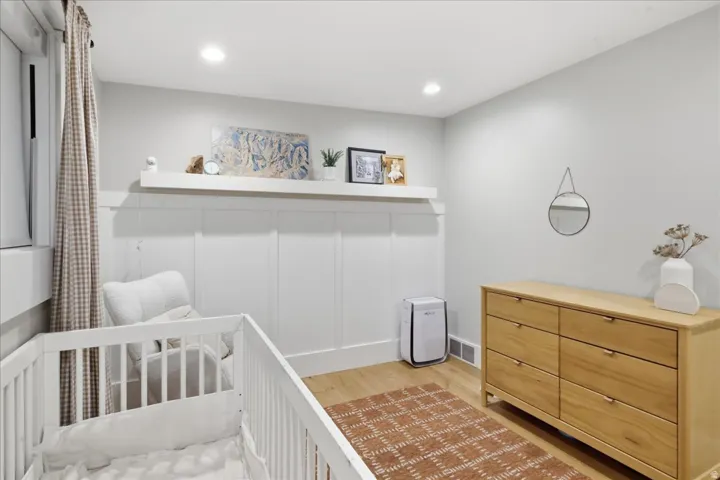 Recessed lighting, wood-finish flooring, white board and batten wall treatment, white wall shelving, and light gray wall paint
