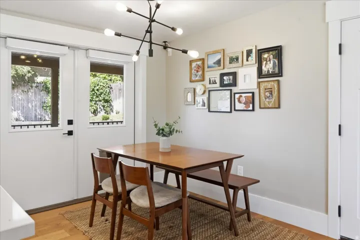 Bright dining area with wood-finish flooring, large dual French doors with transoms opening to exterior space, and a modern sputnik-style ceiling fixture