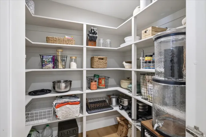 Built-in corner pantry shelving with white finishes and wood-finish flooring