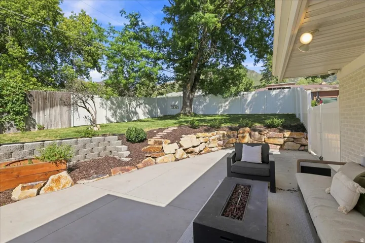 Concrete patio with an adjacent landscaped retaining wall, a raised planter box, and a terraced lawn area