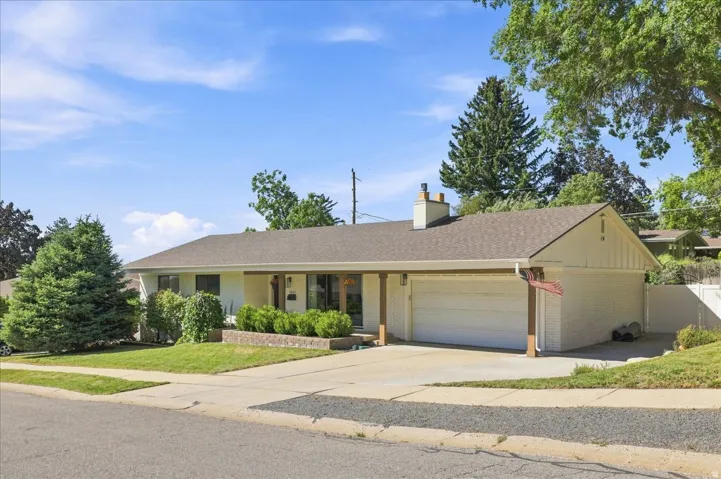 Single-story residence featuring a two-car garage, pitched shingle roof, and a brick chimney