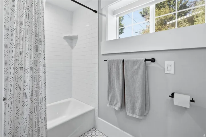 Bathtub with white subway tile surround, integrated corner shelf, and hexagon tile flooring