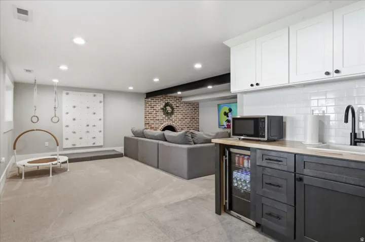 Brick fireplace surround, recessed ceiling lighting, built-in beverage refrigerator, wood-finish countertop, subway tile backsplash