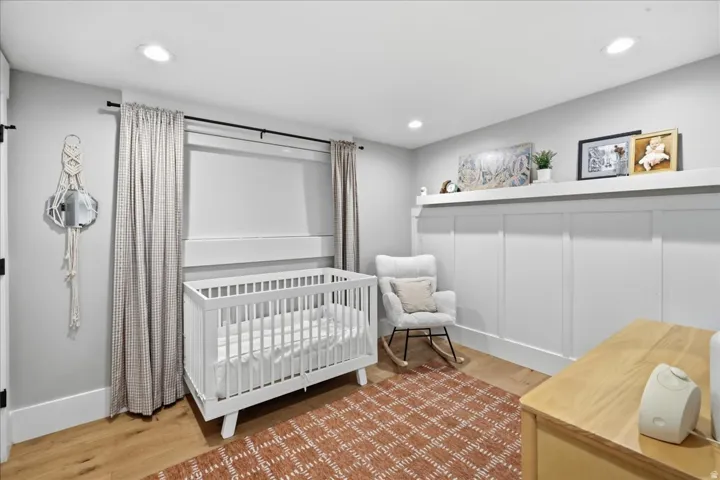 Recessed ceiling lighting, wood-finish flooring, and a decorative wall paneling with an integrated shelf
