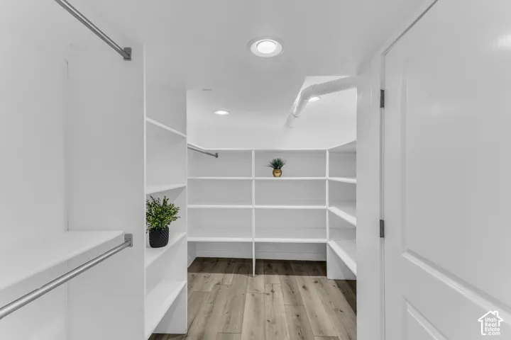 The primary closet is almost as big as some bedrooms! Built-in shelving, hanging rods, recessed lighting, and wood-finish flooring